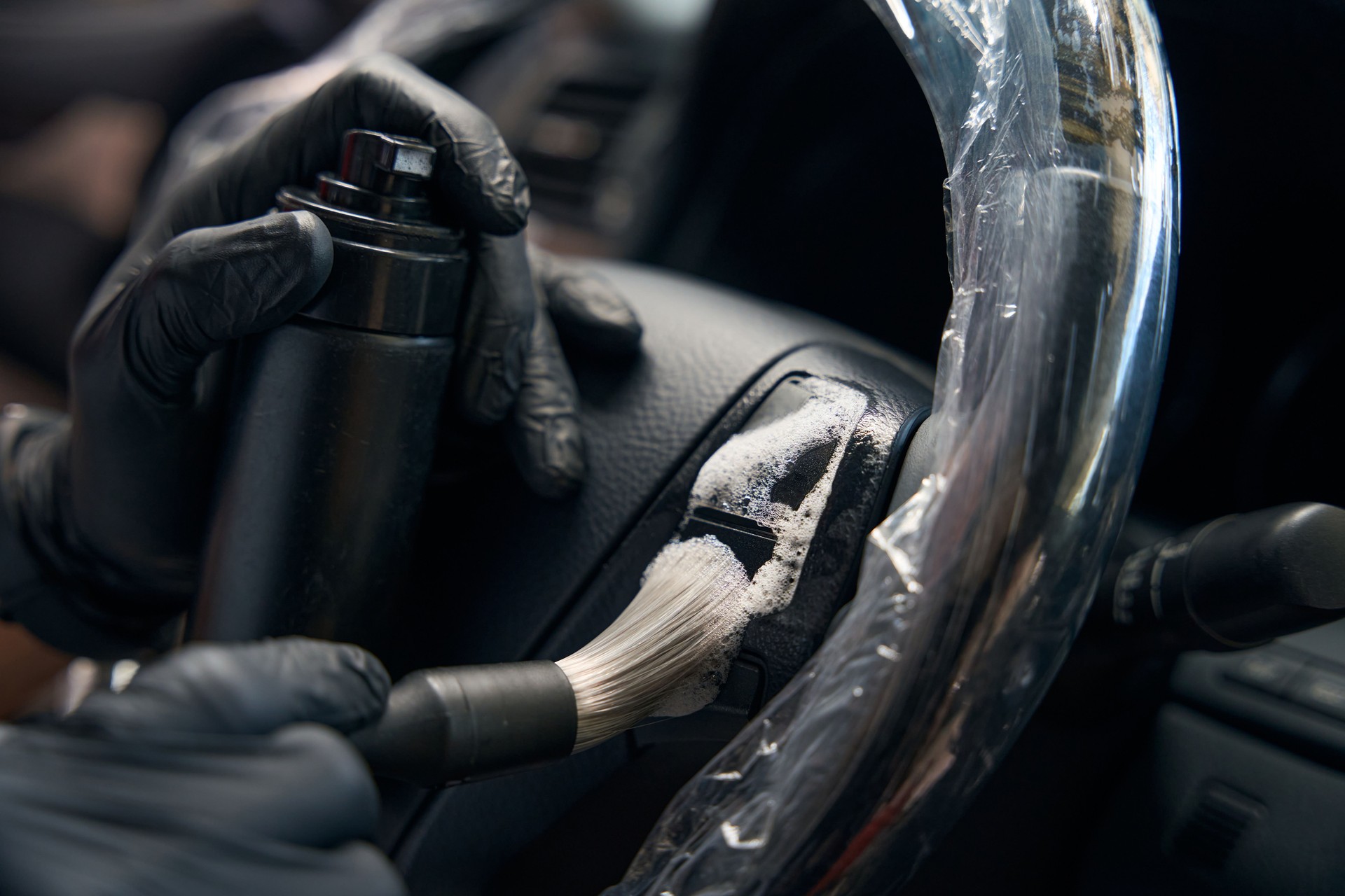 Specialist wearing protective gloves carries out detailing inside the car